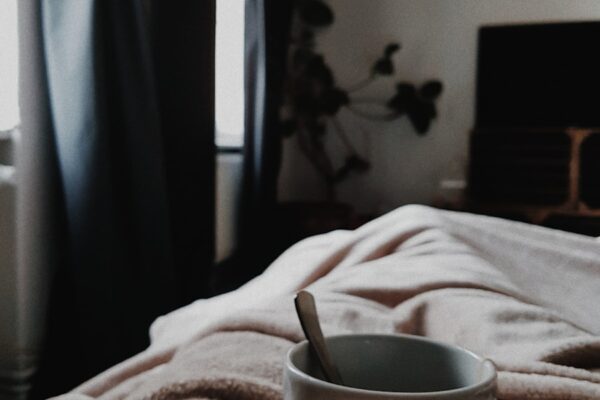 white ceramic mug on bed