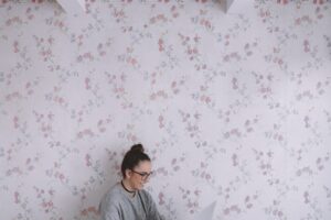 woman holding white ceramic cup while using laptop